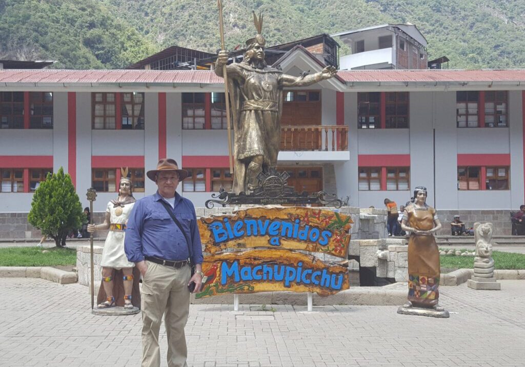 Man standing by Machu Picchu welcome sign